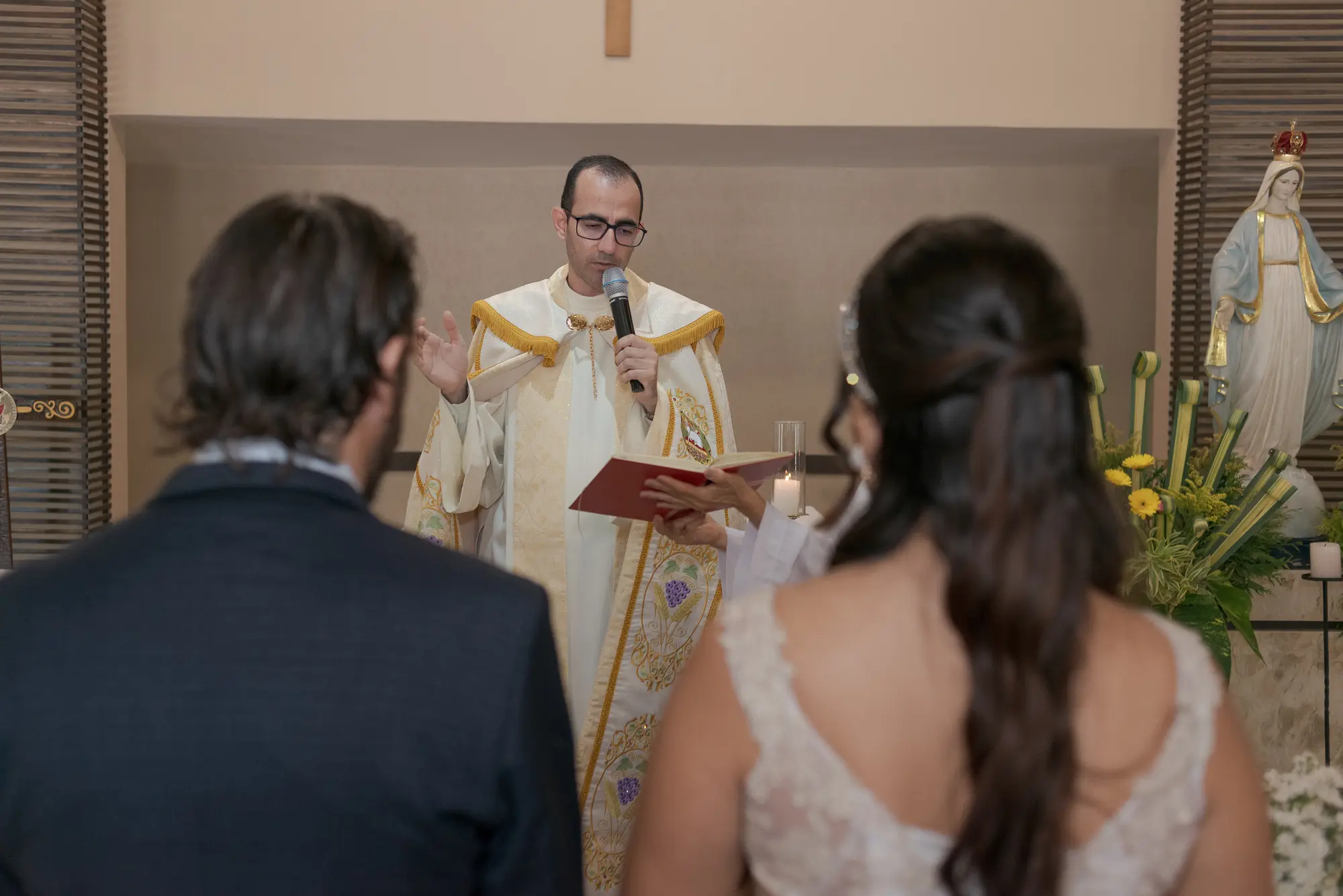 Casal diante do celebrante durante a cerimônia religiosa