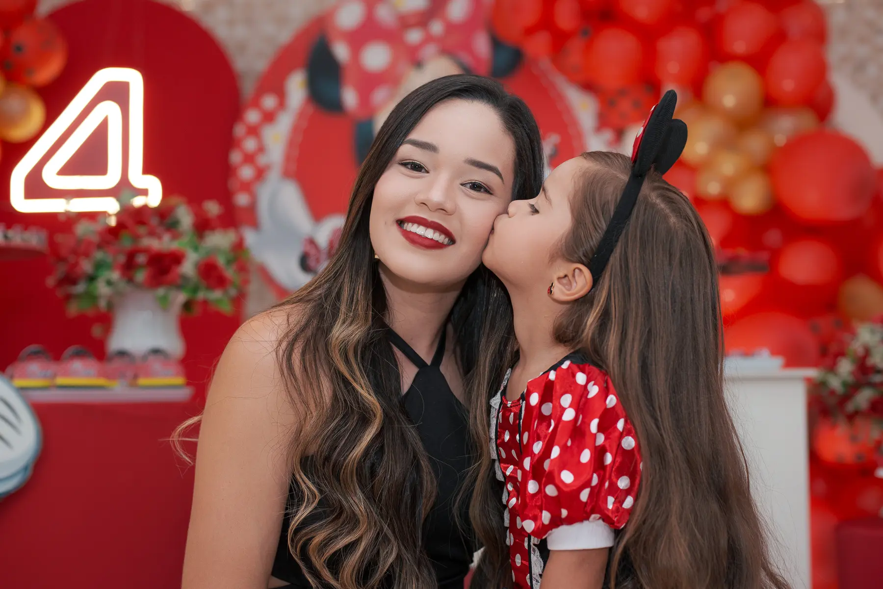 Cloe beijando a mãe diante da decoração da festa