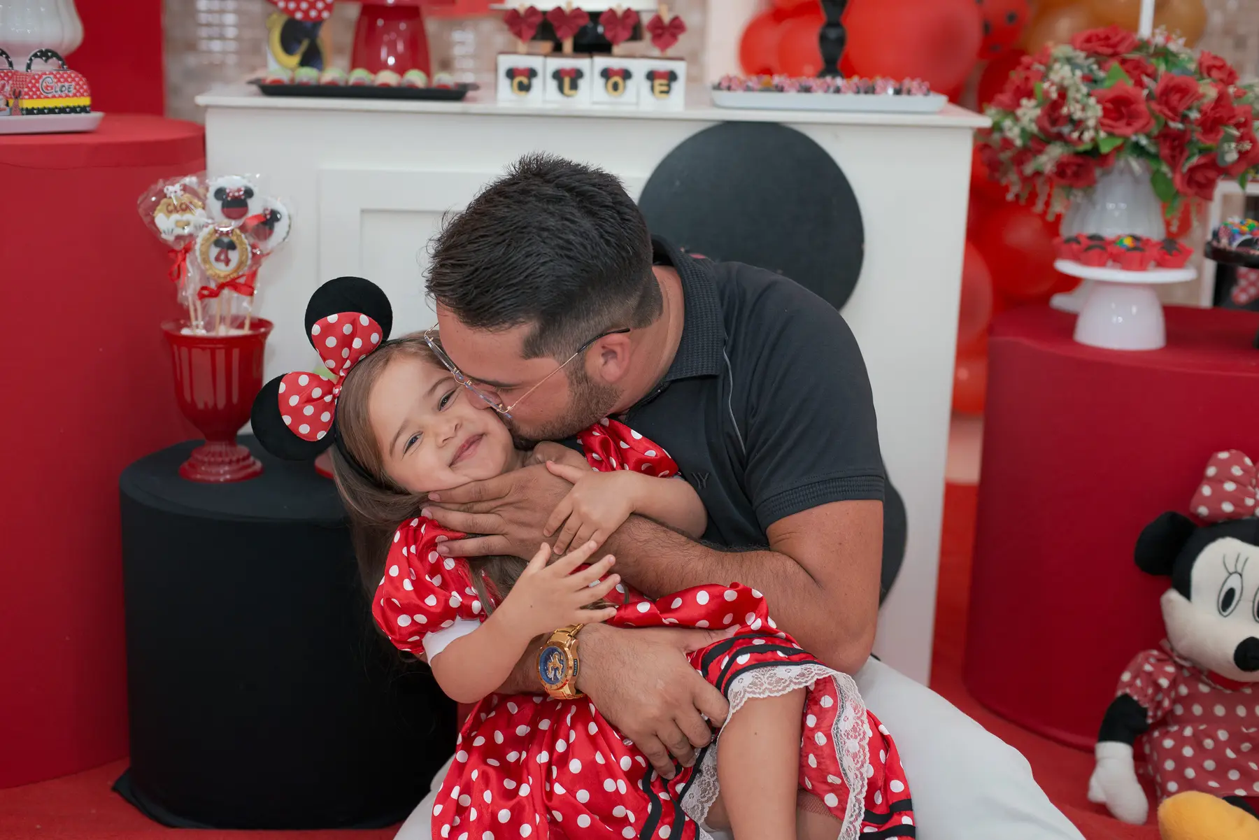Cloe recebendo um beijo do pai durante a festa infantil