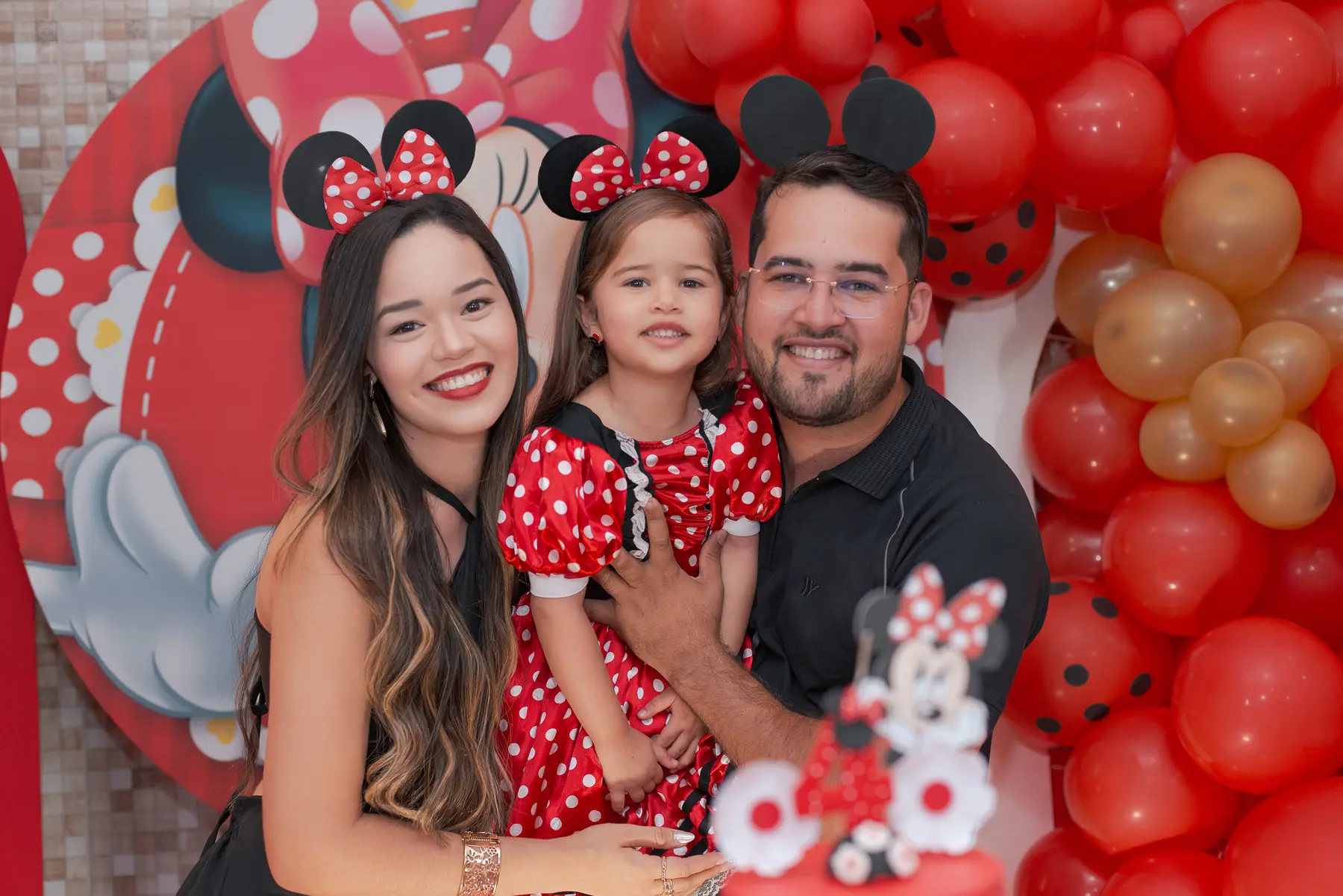 Cloe e os pais sorrindo juntos durante o aniversário