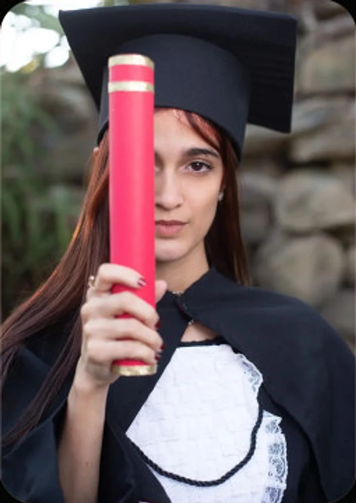 Formanda com beca e diploma em ensaio de conclusão de curso