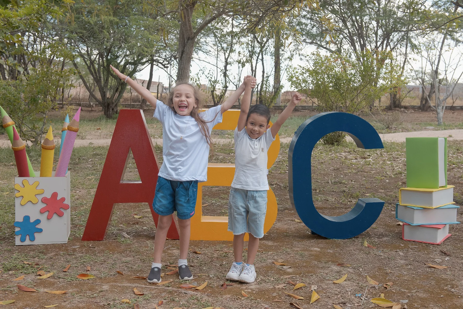 Crianças brincando diante das letras ABC durante ensaio de formatura infantil em Caruaru