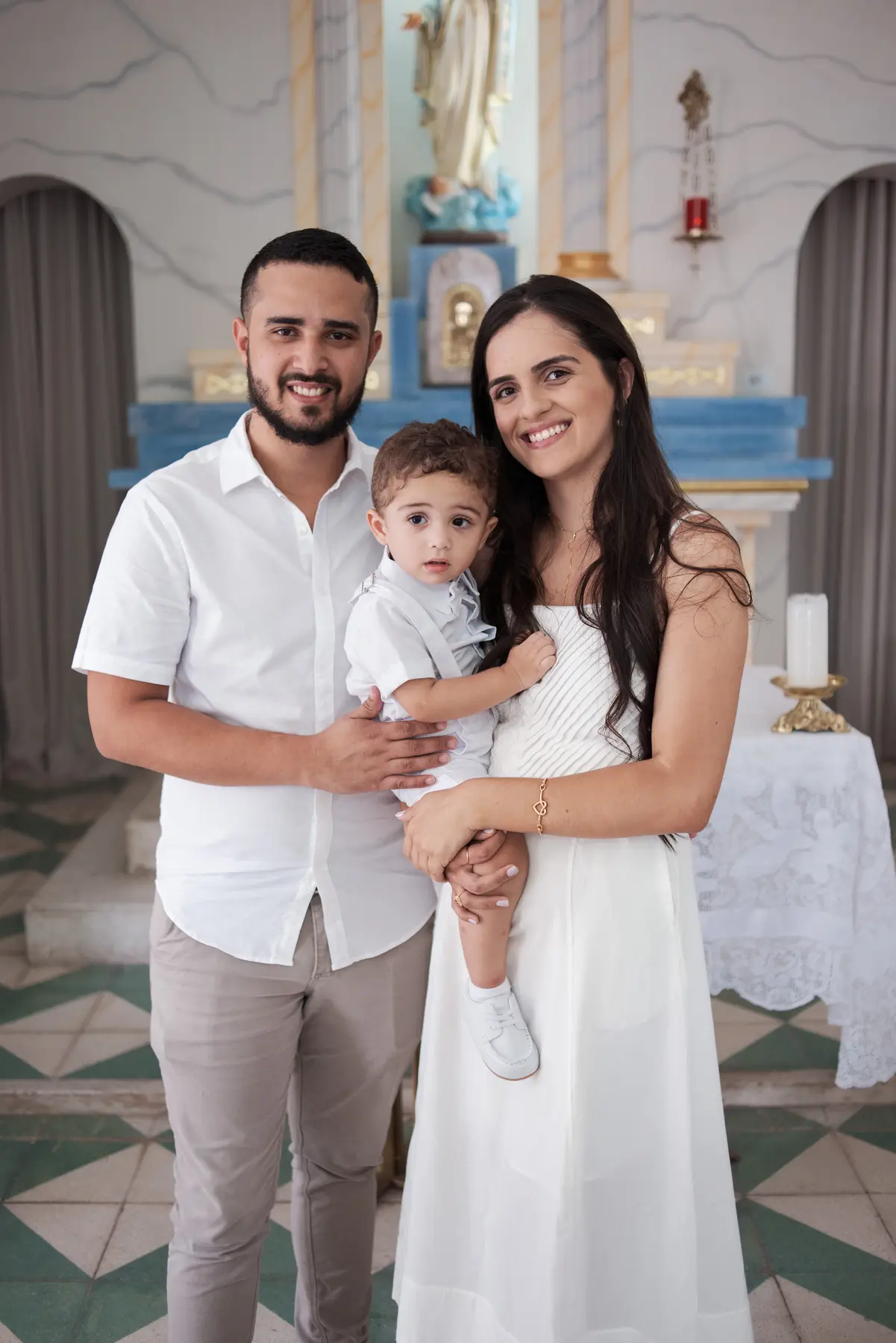 Heitor com os pais diante do altar da Igreja da Natividade, em Caruaru