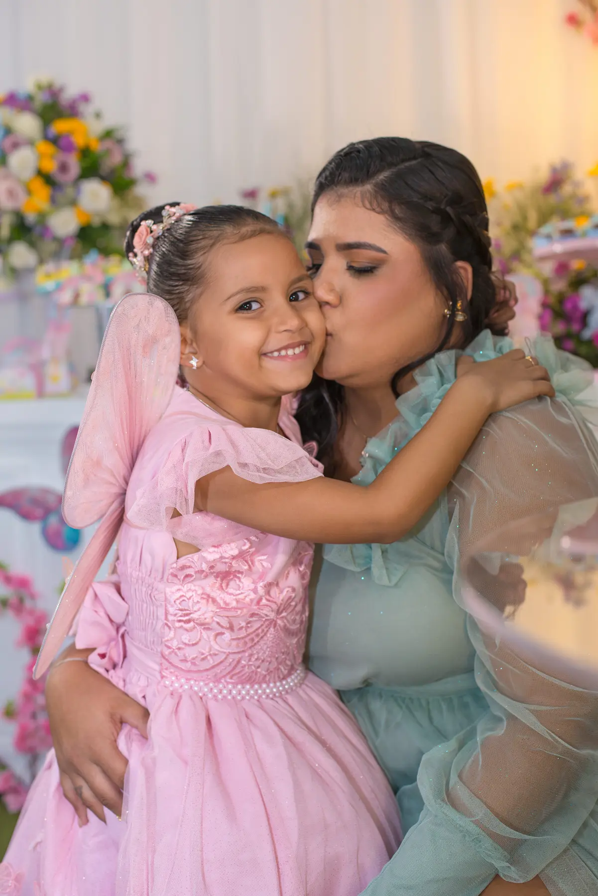 Heloisa recebendo um beijo da mãe durante o aniversário