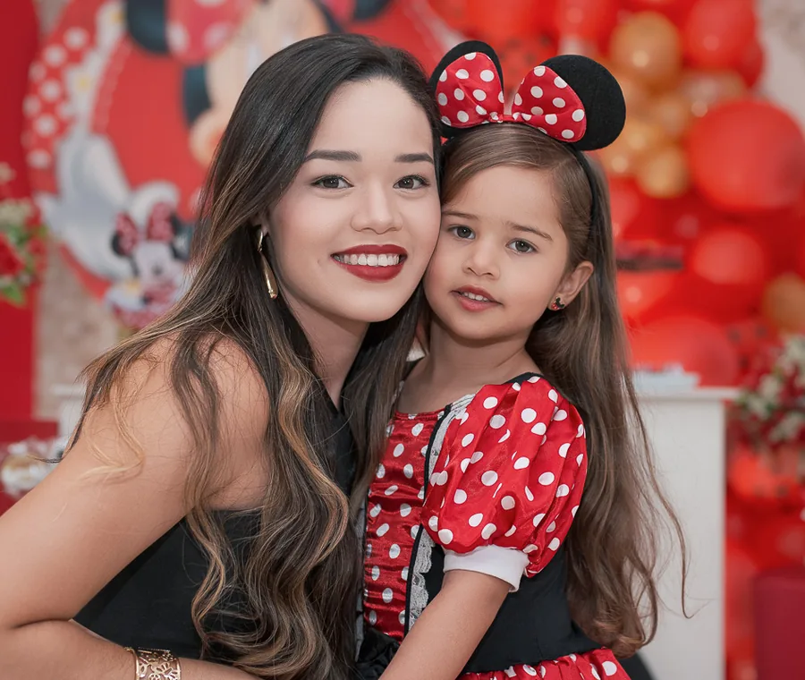 Mãe e filha sorrindo em festa infantil temática.