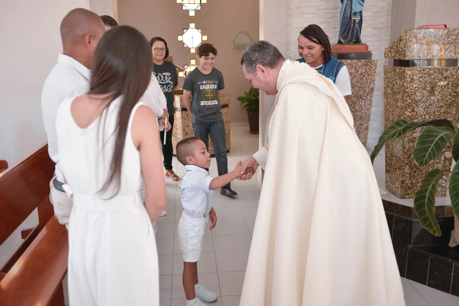 Pietro cumprimentando o padre durante o batizado na Paróquia de São José, em Caruaru